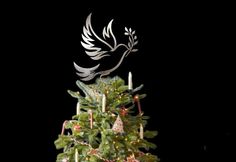 a decorated christmas tree with candles in the shape of a dove on top and an ornament above it