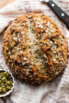 a loaf of bread sitting on top of a table next to two bowls filled with seeds