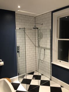 a black and white checkered floor bathroom with a walk in shower next to a window