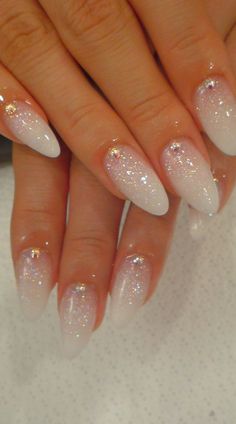 a woman's nails with white and gold glitters