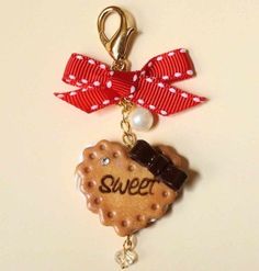 a cookie shaped keychain with a red bow on it's side that says sweet