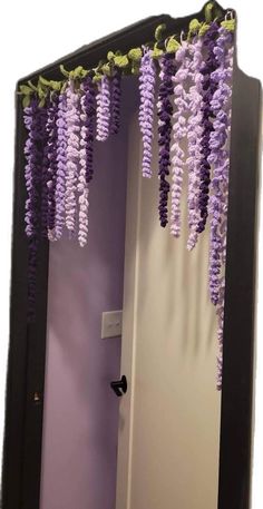 purple flowers are hanging from the ceiling in front of a mirror that is decorated with black frame