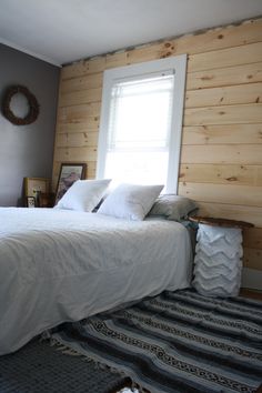 a white bed sitting in a bedroom next to a window with a wreath on top of it