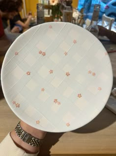 a person holding up a white plate with flowers on it