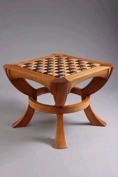 a wooden table with black and white chess pieces on it's top, sitting in front of a gray background