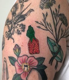 a close up of a person's arm with tattoos on it and flowers in the background