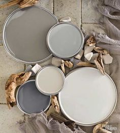 three paint cans sitting on top of a tile floor next to dried up driftwood