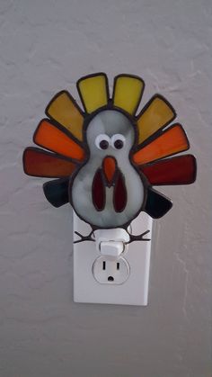 a light switch cover with a glass turkey on it's face and an orange tail