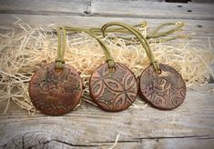 three handmade leather tags sitting on top of hay