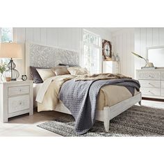 a white bed sitting in a bedroom next to a dresser and mirror on top of a rug