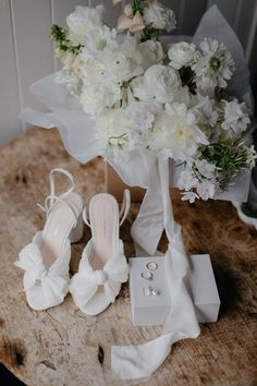 a bouquet of white flowers sitting next to two pairs of shoes on top of a table