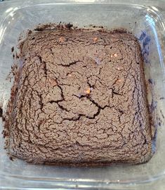 a square cake in a glass dish with brown icing on the top and chocolate sprinkles on the bottom