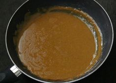 a pan filled with brown sauce on top of a stove