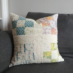 a gray couch with a colorful patchwork quilted pillow on it's back