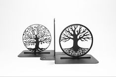 two metal sculptures with trees on them sitting on top of each other in front of a white background