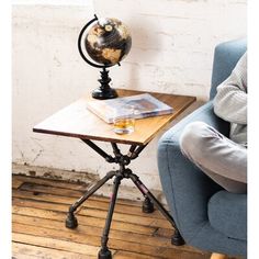 a person sitting in a chair with a book and a globe on top of a table