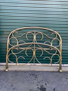 a gold metal bed frame sitting in front of a green garage door