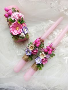 two pink candles are decorated with flowers and burlocks on a lace tablecloth