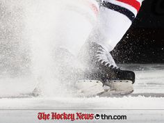 the legs and feet of an ice hockey player are sprinkled with snow as he skates