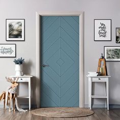 a blue door in a white room with pictures on the wall and rugs around it