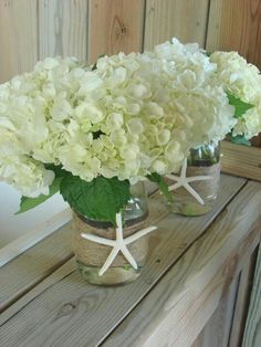 three vases filled with white flowers on top of a wooden table