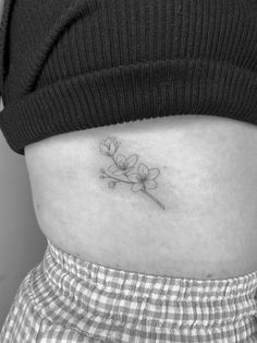 a woman's stomach with a small flower tattoo on the side of her belly