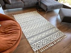 a living room filled with furniture and a rug on top of a hard wood floor