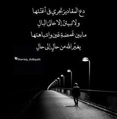 a person walking down a street at night with an arabic quote on the back ground