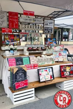 an outdoor market with various items for sale on the tables and in front of it