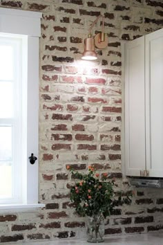 a vase filled with flowers sitting on top of a kitchen counter next to a window