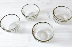 four clear glass cups sitting on top of a white table