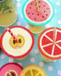 four plastic fruit coasters sitting on top of a table next to lemon slices and mint