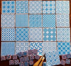 blue and white tiles laid out on a table with a pair of scissors next to them