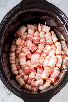 ham wrapped in bacon sitting inside an electric crockpot on a marble counter top