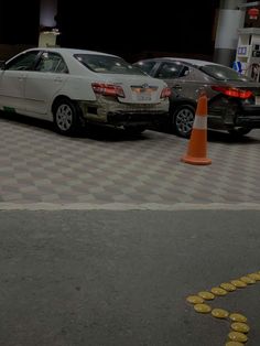 two cars parked next to each other in a parking lot with traffic cones around them