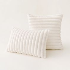 several white pillows stacked on top of each other in front of a white wall and floor