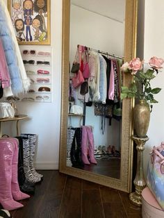 a mirror sitting on top of a wooden floor next to a vase filled with flowers