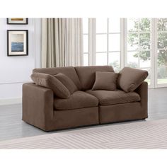 a brown couch sitting on top of a wooden floor next to a white rug and window