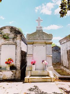 two headstones with flowers on them in front of a cross and sky behind them