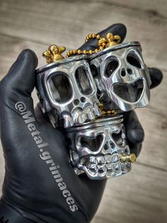 a hand holding a silver and black motorcycle engine with gold skulls on it's head