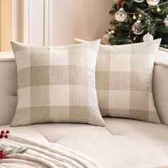 two pillows sitting on top of a couch next to a christmas tree