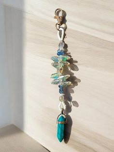 a long beaded necklace hanging from a hook on a wall with beads and stones