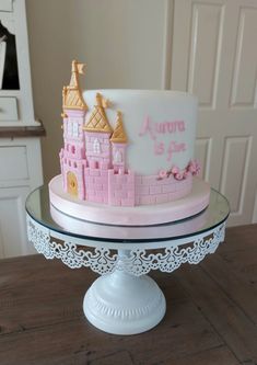 a pink and white cake with castle decorations on it sitting on a glass platter