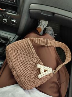 a crocheted purse sitting on top of a car seat next to a steering wheel