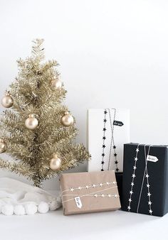 a small christmas tree next to two presents and a black box with gold ornaments on it