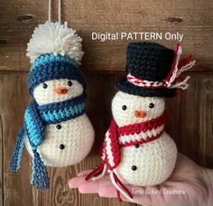 two crocheted snowmen with hats and scarfs hanging on a wooden wall