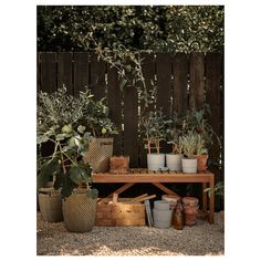 several potted plants are sitting on a table in front of a fence and wooden bench