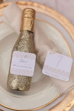 a bottle of champagne sitting on top of a white plate next to a gold and silver napkin