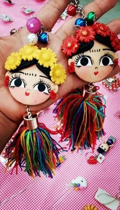 two little dolls are hanging from some kind of keychain on a pink table