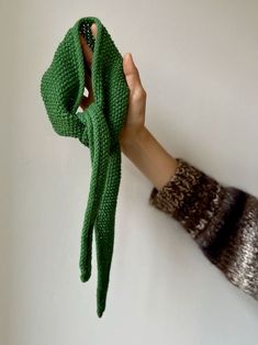 a hand holding a green knitted scarf